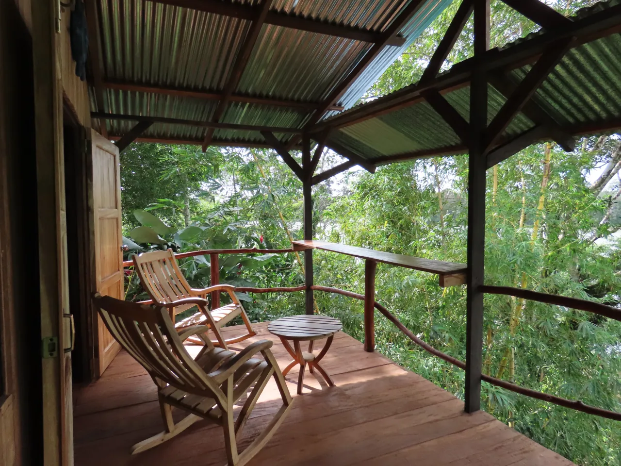 Terraza techada de una cabaña de La Mariola con mecedoras de madera y vista al bosque.